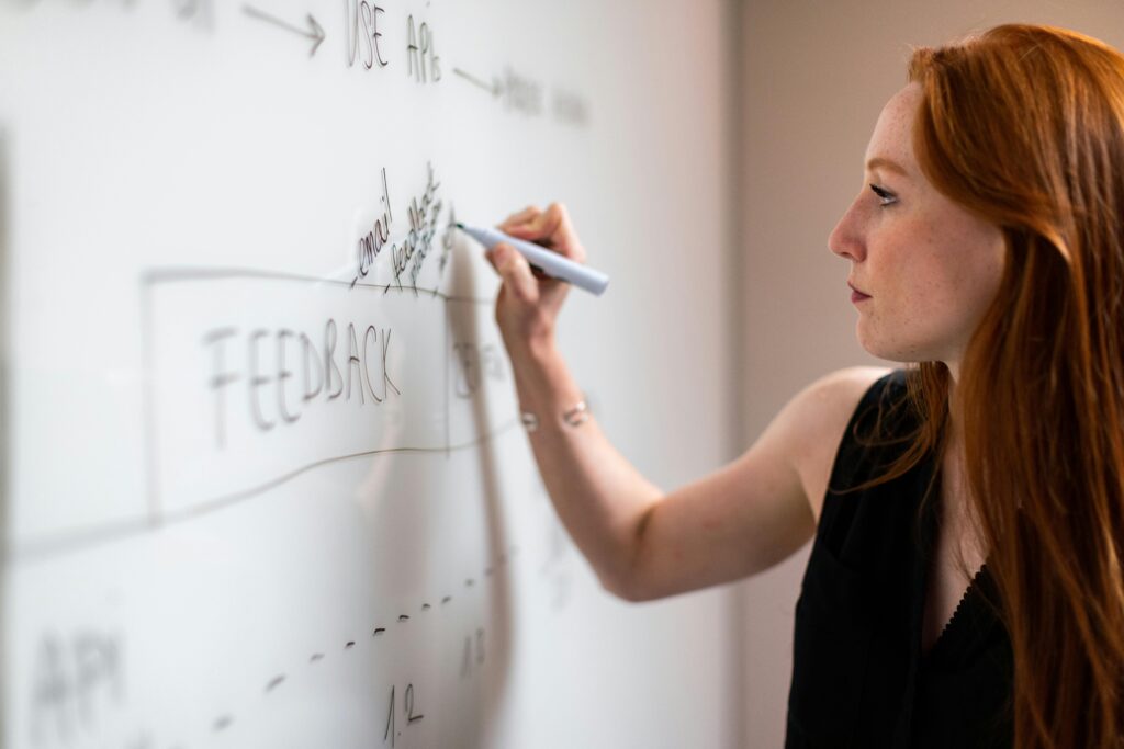 pexels photo 3861970 3861970 Focused woman writing on a whiteboard during a business planning session.